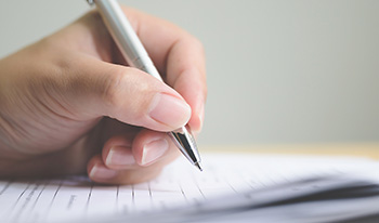 hand holding a pen signing forms