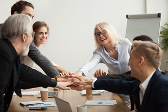 People around a table reaching out with hands on top of each other