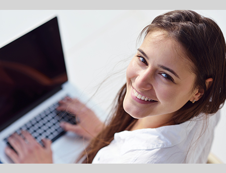 Happy, young teacher working on her laptop